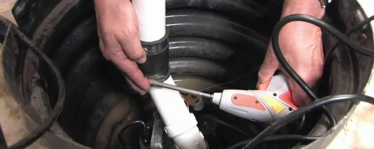 Sump pump installation technician connecting PVC discharge piping in Burlington, VT